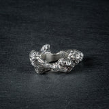 Side view of silver ring 'KUILUUN' – dramatic, abyss-inspired design with shadowed inner structure on slate