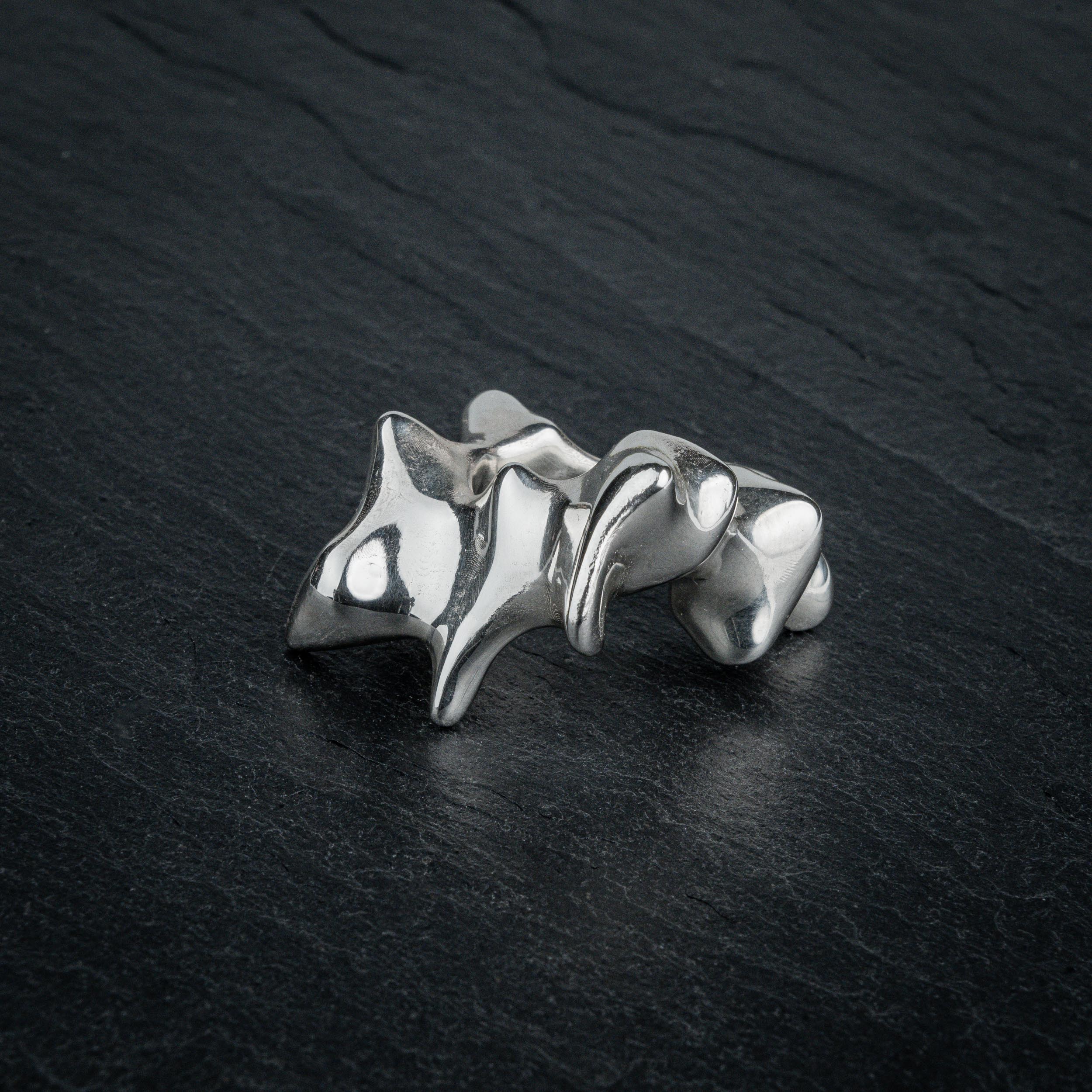 SYRINX organic massive silver sculptural statement ring on dark slate, front view
