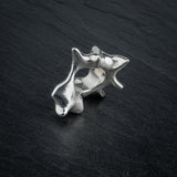 SYRINX organic massive silver sculptural statement ring standing on dark slate, side view