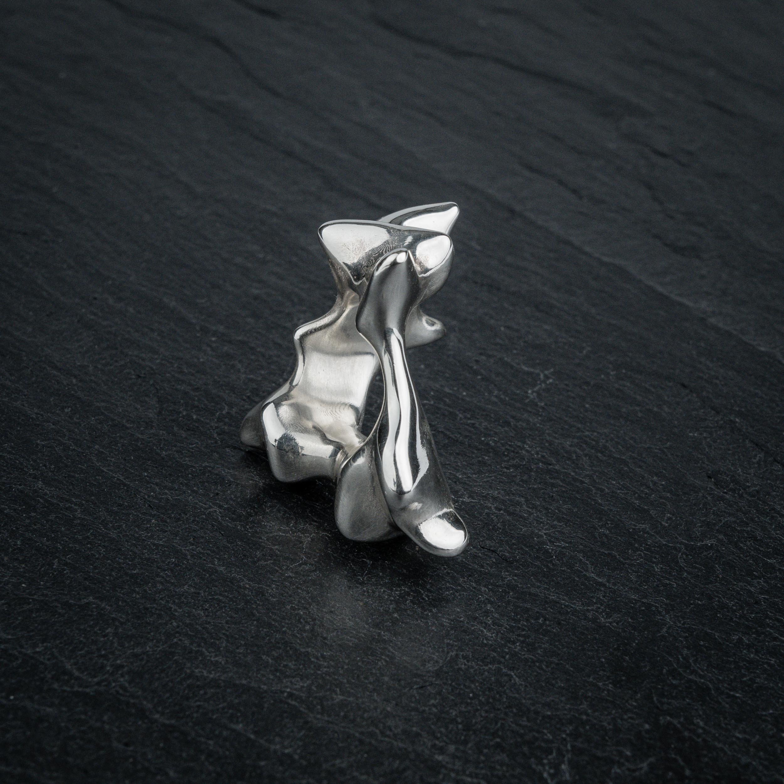 SYRINX organic massive silver sculptural statement ring standing on dark slate, back view