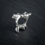 SYRINX organic massive silver sculptural statement ring standing on dark slate, view through ring