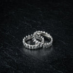 TAKULA two interlocking silver rings inspired by shark teeth, partially overlapping on dark slate