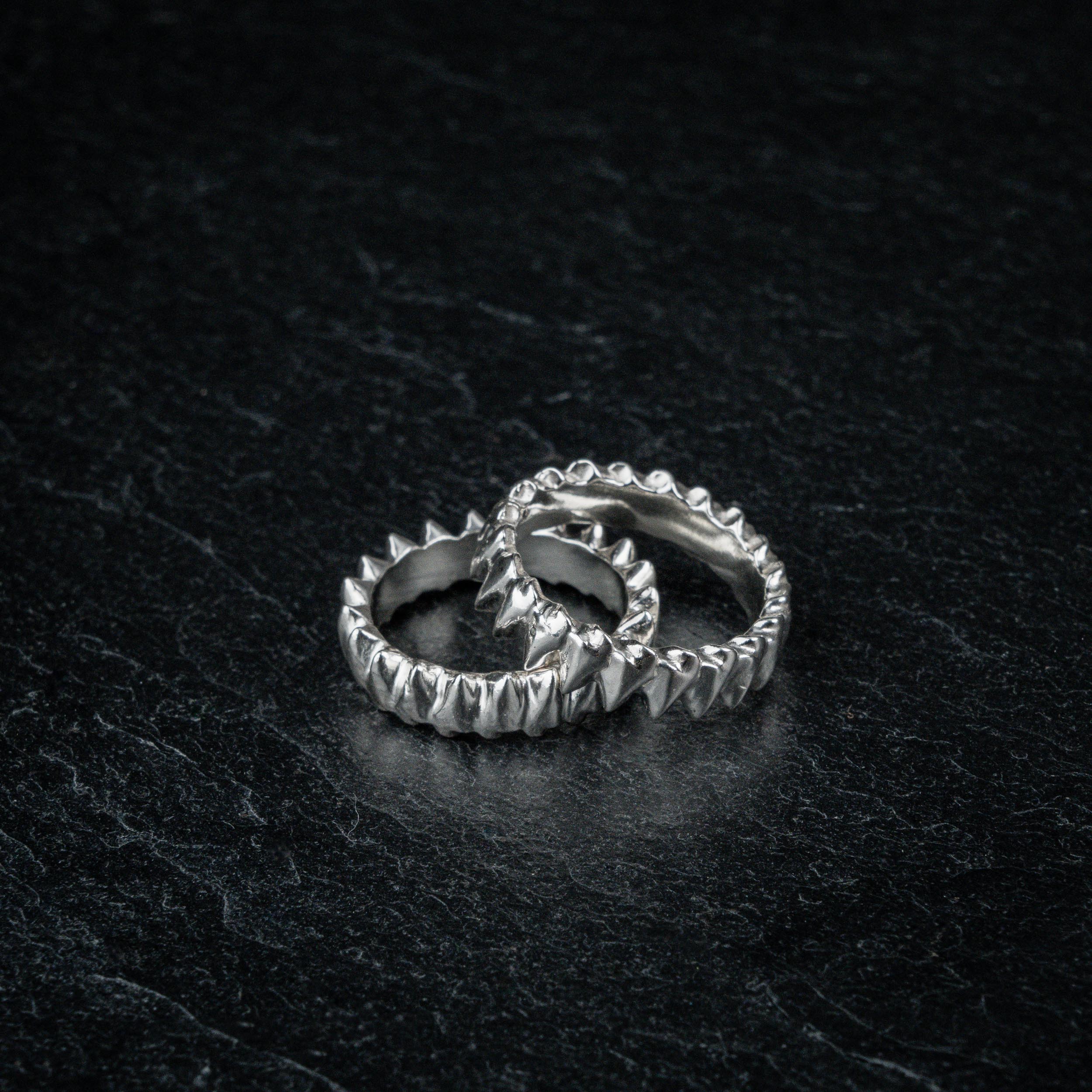 TAKULA two interlocking silver rings inspired by shark teeth, partially overlapping on dark slate