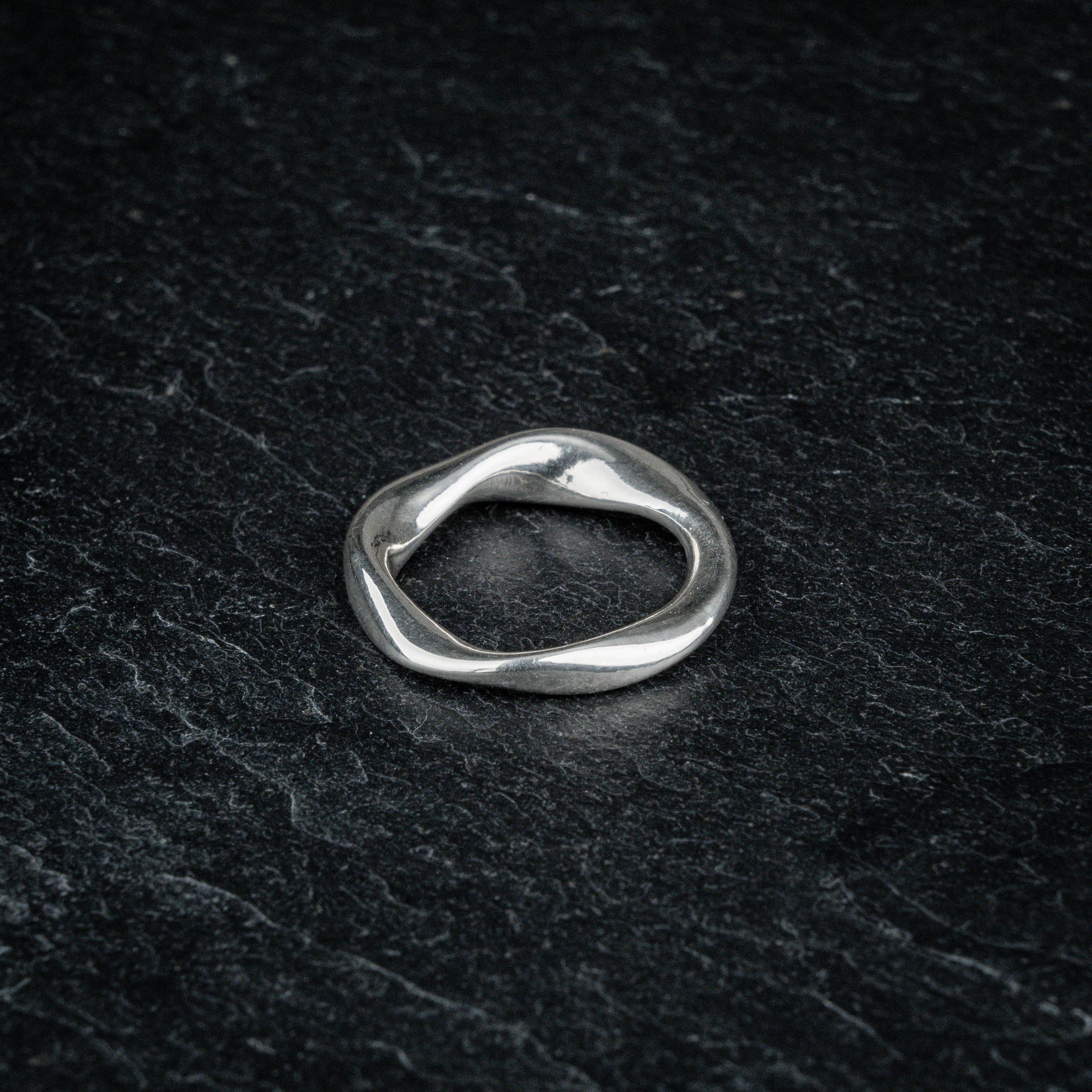 TRI_M72 single silver Möbius strip ring featuring 720 degree twist, solo on slate