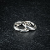 TRI_M three stackable silver Möbius strip rings partially overlapping on slate