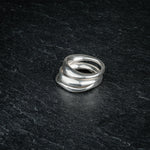 TRI_M three stackable silver Möbius strip rings stacked on top of each other on slate