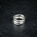 TRI_M three stackable silver Möbius strip rings layered on top of each other on slate