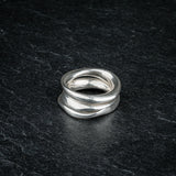 TRI_M three stackable silver Möbius strip rings layered on top of each other on slate