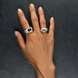 YUHI two massive silver sculptural rings evoking sunrays with onyx and moonstone worn on hand
