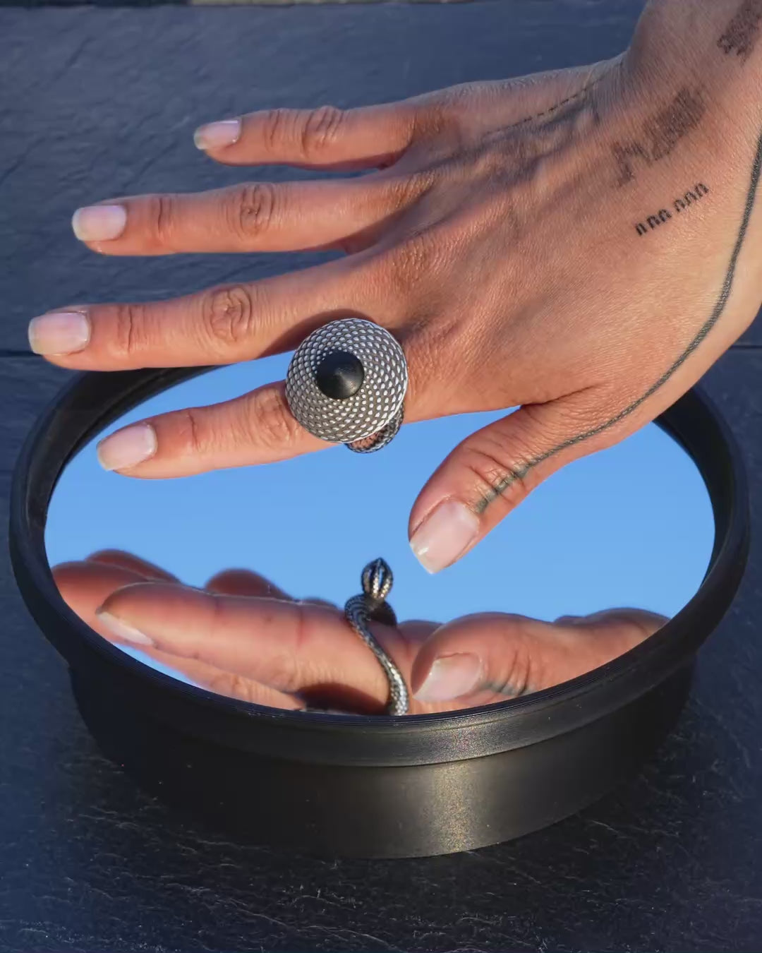 PHI worn as silver ring on hand, then spinning as kinetic sculpture on mirror base